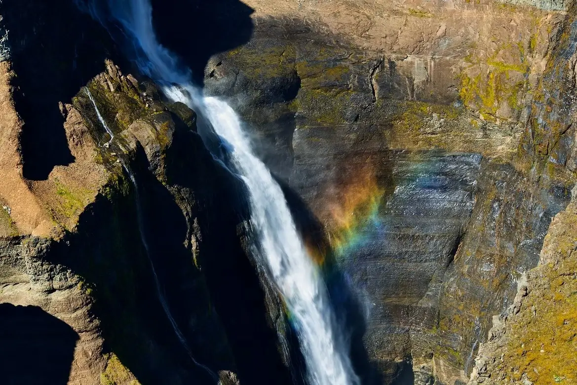 A rainbow emanating from the pit of a waterfall
